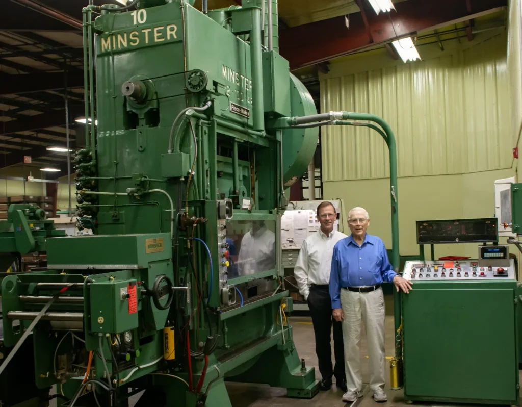 PAX Machine Works founders standing beside a Minster stamping press